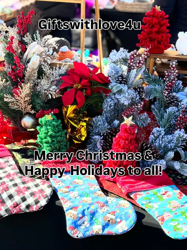 A holiday market table with crochet Christmas trees, a poinsettia, frosted greenery and Christmas stockings.