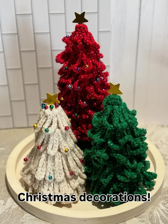 Three crochet Christmas trees in red, green and cream, dotted with tiny bead ornaments and topped with gold stars.